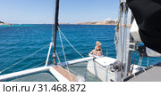 Woman relaxing on a summer sailing cruise, sitting on a luxury catamaran near picture perfect white sandy beach on Spargi island in Maddalena Archipelago, Sardinia, Italy. Стоковое фото, фотограф Matej Kastelic / Фотобанк Лори