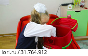 First-grader checks the completeness of her backpack in front of the school. Стоковое видео, видеограф Aleksandr Sulimov / Фотобанк Лори