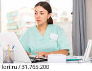 Practicioner girl in medical uniform is working at laptop. Стоковое фото, фотограф Яков Филимонов / Фотобанк Лори