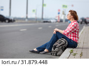 Mature woman hitchhiker sitting on roadside and waiting the car. Стоковое фото, фотограф Кекяляйнен Андрей / Фотобанк Лори
