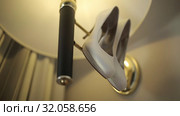 White shoes hang on the lamp in the light by the wall Macro shot shot glidetrack. Стоковое видео, видеограф Aleksejs Bergmanis / Фотобанк Лори