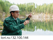 Industrial ecologist takes a sample of water from lake at the site of a flooded quarry. Стоковое фото, фотограф Евгений Харитонов / Фотобанк Лори