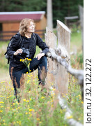 Middle age Caucasian woman bird watcher stands near wooden fence with binoculars for birdwatching as a hobby. Стоковое фото, фотограф Кекяляйнен Андрей / Фотобанк Лори