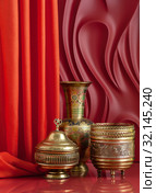 Copperware in oriental style on a red background with theatrical design. Стоковое фото, фотограф Olesya Tseytlin / Фотобанк Лори