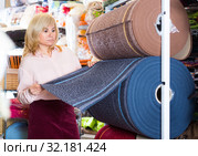 Mature woman customer choosing colored carpeting. Стоковое фото, фотограф Яков Филимонов / Фотобанк Лори