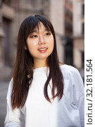Portrait of cheerful young chinese longhaired woman standing on a city street. Стоковое фото, фотограф Яков Филимонов / Фотобанк Лори