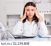 Upset practicioner girl is working with documents and laptop. Стоковое фото, фотограф Яков Филимонов / Фотобанк Лори