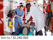 mature afro paramedical using defibrillator for providing medical care to patient. Стоковое фото, фотограф Яков Филимонов / Фотобанк Лори