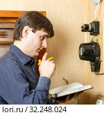The man takes the readings of the apartment electric meter and writes it in the notebook. Стоковое фото, фотограф Акиньшин Владимир / Фотобанк Лори