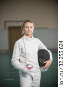 A young smiling woman fencer standing in the gym holding sword and helmet. Стоковое фото, фотограф Константин Шишкин / Фотобанк Лори