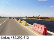 Строительство новой современной автомобильной дороги Таврида в Крыму. Свежий черный асфальт отделен желтыми и красными дорожными барьерами. Солнечный летний день. Стоковое фото, фотограф Наталья Гармашева / Фотобанк Лори