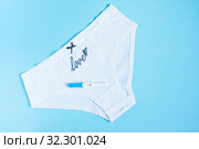 Female white panties with bow and word love and negative pregnancy test on blue background. Health care, Infertility, contraception and planned pregnancy. Стоковое фото, фотограф Papoyan Irina / Фотобанк Лори