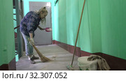 A young woman in blue jeans and a cage shirt swings and washes the floor on a staircase next to an elevator in a Stalinist-built apartment building, Cleaning public spaces by a labor immigrant cleane. Стоковое видео, видеограф Куликов Константин / Фотобанк Лори