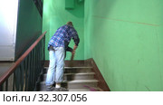 A young woman in blue jeans and a cage shirt swings and washes the floor on a staircase next to an elevator in a Stalinist-built apartment building, Cleaning public spaces by a labor immigrant cleane. Стоковое видео, видеограф Куликов Константин / Фотобанк Лори