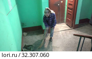A young woman in blue jeans and a cage shirt swings and washes the floor on a staircase next to an elevator in a Stalinist-built apartment building, Cleaning public spaces by a labor immigrant cleane. Стоковое видео, видеограф Куликов Константин / Фотобанк Лори