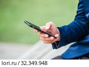 Closeup of male hands is holding cellphone outdoors on the street. Man using mobile smartphone. Стоковое фото, фотограф Дмитрий Травников / Фотобанк Лори