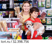 Careful preteen boy with mother visiting pet shop in search of treats for their dog. Стоковое фото, фотограф Яков Филимонов / Фотобанк Лори