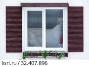 White plastic pvc window with decorative wooden shutters and Christmas lights inside, outdoor facade. Стоковое фото, фотограф Кекяляйнен Андрей / Фотобанк Лори