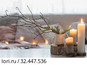 Composition of candles on white table against the background of sofa with plaids and pillows. Cozy home concept. Стоковое фото, фотограф Майя Крученкова / Фотобанк Лори