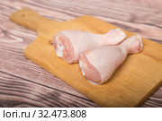 Two raw chicken legs on a cutting board lie on wooden table. Стоковое фото, фотограф Юлия Бабкина / Фотобанк Лори