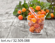 Морошка среди листьев на сером деревянном фоне. Стоковое фото, фотограф Наталья Осипова / Фотобанк Лори