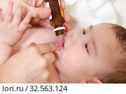Medical drops oral vaccination to infant for immunisation. Mother holds glass bottle with liquid medicament. Стоковое фото, фотограф Кекяляйнен Андрей / Фотобанк Лори