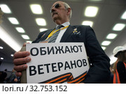 Журналист с плакатом с надписью "Обижают ветеранов" перед началом большой ежегодной пресс-конференции Владимира Путина, Россия 19 декабря 2019. Редакционное фото, фотограф Николай Винокуров / Фотобанк Лори
