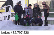 Дети катаются с ледяной горки на городской площади. Children ride on an ice slide in the town square. (2019 год). Редакционное видео, видеограф Евгений Романов / Фотобанк Лори