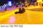 Дети катаются с ледяной горки на городской площади. Children ride on an ice slide in the town square. (2019 год). Редакционное видео, видеограф Евгений Романов / Фотобанк Лори