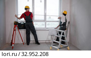 Apartment repair in the room - two men workers measuring the window. Стоковое фото, фотограф Константин Шишкин / Фотобанк Лори