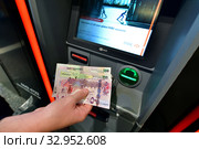 Doha, Qatar - Nov 17. 2019. Qatari rials in hand on the background of ATM of HSBC Bank. Редакционное фото, фотограф Володина Ольга / Фотобанк Лори