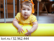 Little girl portrait, baby lying on yellow foam roller in domestic gym, looking at camera. Стоковое фото, фотограф Кекяляйнен Андрей / Фотобанк Лори