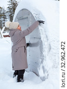 Middle age woman trying to clear the snow away from roof of plastic greenhouse at winter season. Стоковое фото, фотограф Кекяляйнен Андрей / Фотобанк Лори