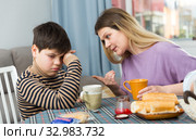 Upset mother and unhappy son arguing during breakfast indoors. Стоковое фото, фотограф Яков Филимонов / Фотобанк Лори