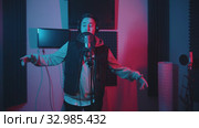A man in hoodie rapping in the studio gesticulates while recording his track. Стоковое видео, видеограф Константин Шишкин / Фотобанк Лори