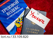 Трудовой кодекс Российской Федерации и трудовая книжка с запиской "Уволить" лежат на столе сотрудника кадровой службы (2020 год). Редакционное фото, фотограф Николай Винокуров / Фотобанк Лори