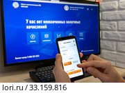 Самозанятость в России. Самозанятый регистрирует новую продажу в мобильном приложении "Мой налог" (2020 год). Редакционное фото, фотограф Иванов Алексей / Фотобанк Лори