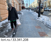 Женщина с замотанным шарфом лицом идет по улице Светланская в начале марта (2020 год). Редакционное фото, фотограф Овчинникова Ирина / Фотобанк Лори