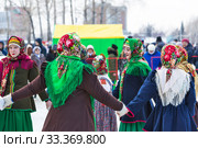 Девушки одетые в национальную старинную русскую одежду и яркие платки водят хоровод на празднике Масленицы. Город Бердск, Новосибирская область, Западная Сибирь, Россия (2020 год). Редакционное фото, фотограф Евгений Мухортов / Фотобанк Лори