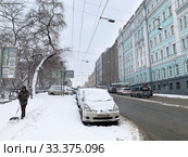 Дворник с лопатой и занесенная снегом машина на Светланской улице во Владивостоке в период мартовского циклона (2020 год). Редакционное фото, фотограф Овчинникова Ирина / Фотобанк Лори