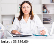 Practicioner girl in medical uniform is working with documents and laptop. Стоковое фото, фотограф Яков Филимонов / Фотобанк Лори