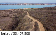 Aerial view, flying over a dirt road in steppe, in the background the pond and village. Camera moving forwards above steppe to the pond side. Khadzhibey Estuary, Odessa region, Ukraine. Стоковое видео, видеограф Некрасов Андрей / Фотобанк Лори