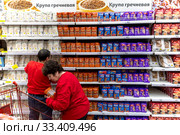 Сотрудники магазина выкладывают упаковки гречки и риса в магазине торговой сети АШАН в торговом центре МЕГА в Химках, Россия (2020 год). Редакционное фото, фотограф Николай Винокуров / Фотобанк Лори