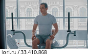 Modern gym - a guy sitting down on the training apparatus and waiting for when it will be possible to start. Стоковое видео, видеограф Константин Шишкин / Фотобанк Лори
