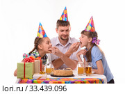 Дети кусают куски торта с рук папы, весело празднуя день рождения. Стоковое фото, фотограф Иванов Алексей / Фотобанк Лори