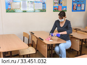 Девушка сыпет чистящее и дезинфицирующее средство на парту в школе в период карантина (2020 год). Редакционное фото, фотограф Иванов Алексей / Фотобанк Лори