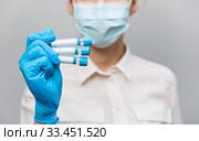 Girl Doctor in medical mask and rubber gloves, holds in her hands, closeup of test tube with tests for the presence of covid-19. Doctor in medical clothes demonstrates test tubes with coronavirus. Стоковое фото, фотограф Сергей Тимофеев / Фотобанк Лори