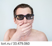Portrait of bare to the waist man with dark glasses, person is shocked covering his mouth with hand. Grey background. Стоковое фото, фотограф Кекяляйнен Андрей / Фотобанк Лори