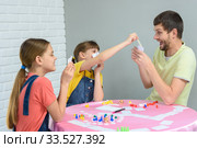 Дети вытягивают у папы карту в веселой настольной игре. Стоковое фото, фотограф Иванов Алексей / Фотобанк Лори