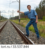 Carefree young man trying to stop a train on a railway. Стоковое фото, фотограф Александр Романов / Фотобанк Лори